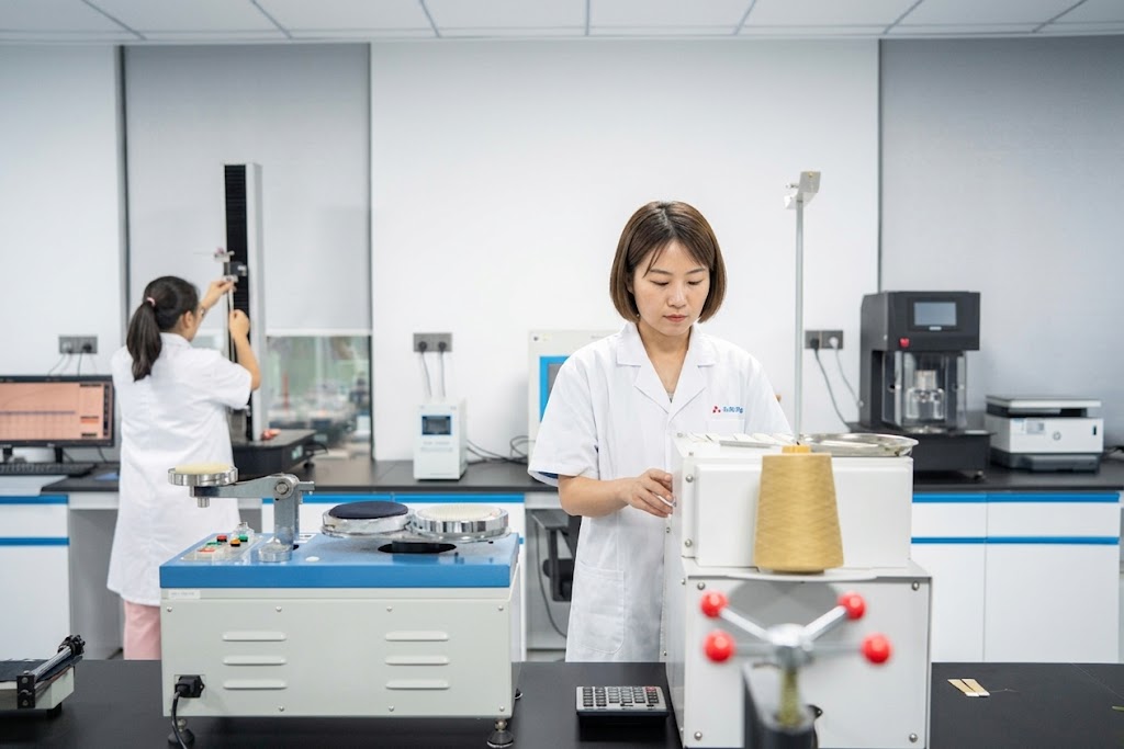 Two professional female technicians conducting rigorous durability and tensile strength testing on athletic textiles in a state-of-the-art fabric laboratory.