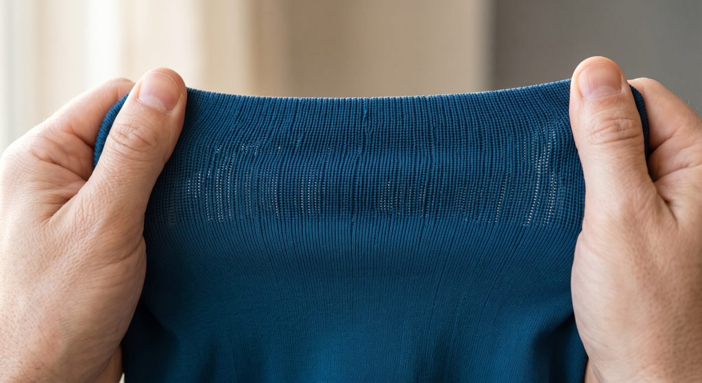Durable nylon activewear knit fabric being stretched to demonstrate tight micro-knit structure, high elasticity, and tear resistance